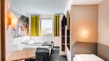 Una habitación de hotel con cama, escritorio, silla, televisor y armario.