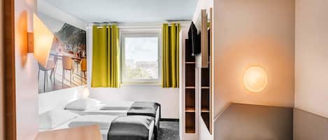Una habitación de hotel con cama, escritorio, silla, televisor y armario.