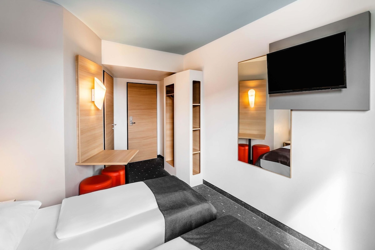 Una camera d'albergo moderna con un divano, una TV a parete e una porta in legno.