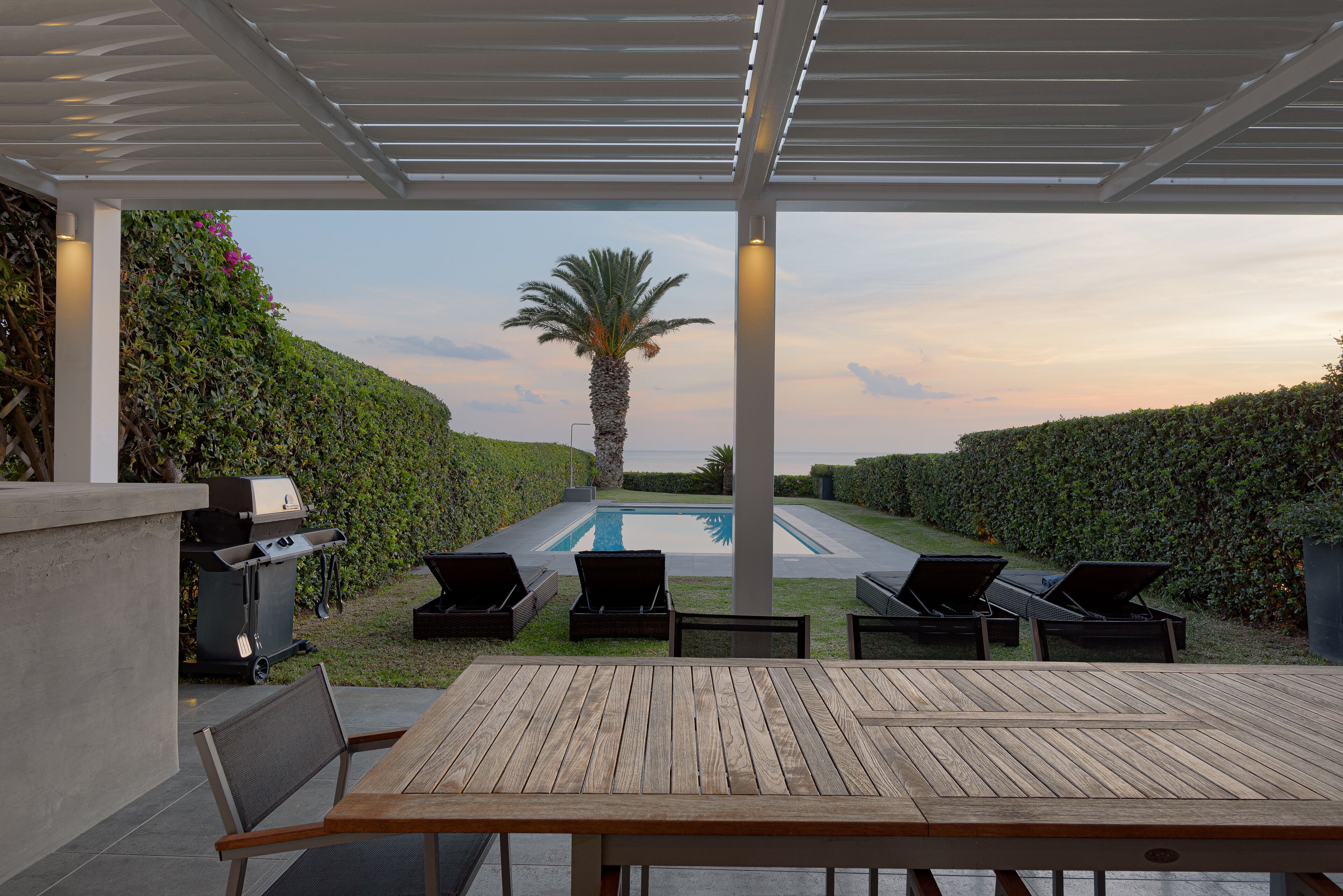 Une terrasse extérieure avec une piscine, des chaises longues et un barbecue.