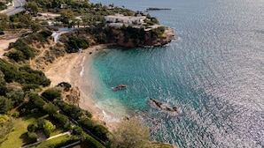 Eine Küstenlandschaft mit Strand, klarem blauen Wasser und einem Bergpanorama im Hintergrund.
