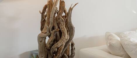Een moderne woonkamer met een witte bank, een houten sculptuur op een tafel en een lamp met een beige lampenkap.
