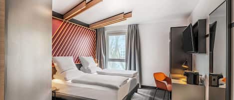 Una habitación de hotel moderna con una cama, un escritorio, una silla y un televisor.