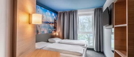 A hotel room with two beds, a wooden desk, a TV, a painting of a cityscape, and a window with curtains.