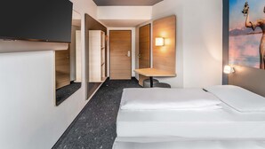 A hotel room with a bed, a desk, a chair, a TV, and a painting on the wall. - B&B Hotel Konstanz (Konstanz)