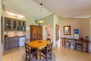 A compact kitchen with a dining area, featuring a round wooden table, chairs, and a hanging light fixture.