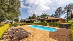 A pool area with lounge chairs, a brick patio, and a clear blue sky. - Stables 90 minutes from São Paulo (Cesário Lange)