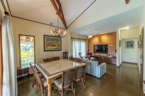 A spacious dining area with a large table and chairs, a television in the living area, and a brick fireplace.