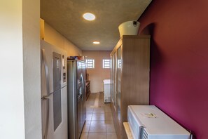 A narrow kitchen with stainless steel appliances, a wooden cabinet, and a window providing natural light.
