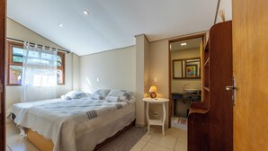 A bedroom with a bed, a bedside table with a lamp, a bathroom with a sink and mirror, and a wooden door. - Stables 90 minutes from São Paulo (Cesário Lange)