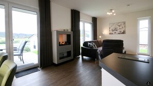 A modern living room with a fireplace, a sofa, and a dining area. - Haus Nina - Sonnenweg 20 (Diemelsee)