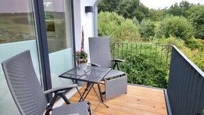 A balcony with wicker furniture, a small table, and a potted plant. - Haus Nina - Sonnenweg 20 (Diemelsee)