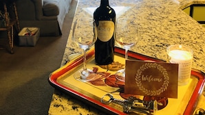 A living room with a dining table, two wine glasses, a bottle of wine, and a candle on a tray. - One of the Best Views in Wintergreen! (Wintergreen Resort)