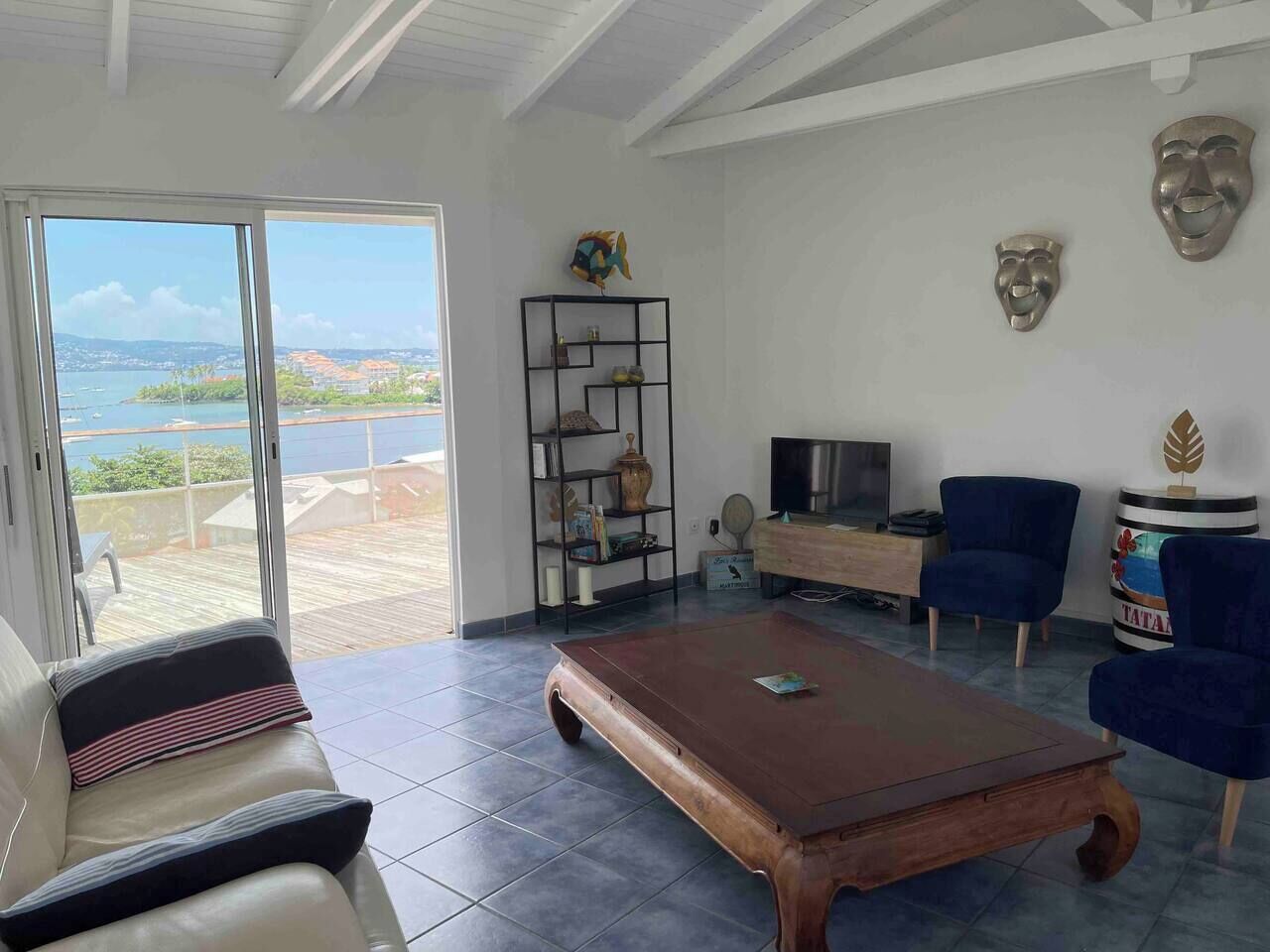 A living room with a large wooden coffee table, a sofa, a TV, and a bookshelf.