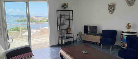 A living room with a large wooden coffee table, a sofa, a TV, and a bookshelf.