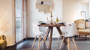 Un coin repas avec une table ronde, des chaises blanches, un vase et un miroir au mur.