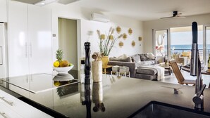 Une cuisine moderne avec un plan de travail noir, des meubles blancs et une grande fenêtre donnant sur la mer.