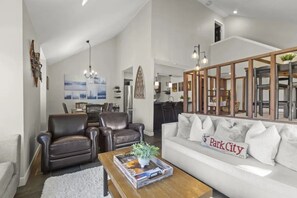 Un salon moderne avec un canapé blanc, des fauteuils en cuir et une table basse.