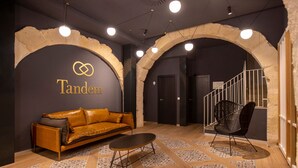 A modern interior with a leather sofa, a black chair, and a patterned floor. - Tandem Portal de Elche (Alicante)