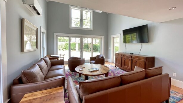 Een moderne woonkamer met een modulaire bank, een salontafel en een flatscreen televisie die aan de muur is bevestigd.