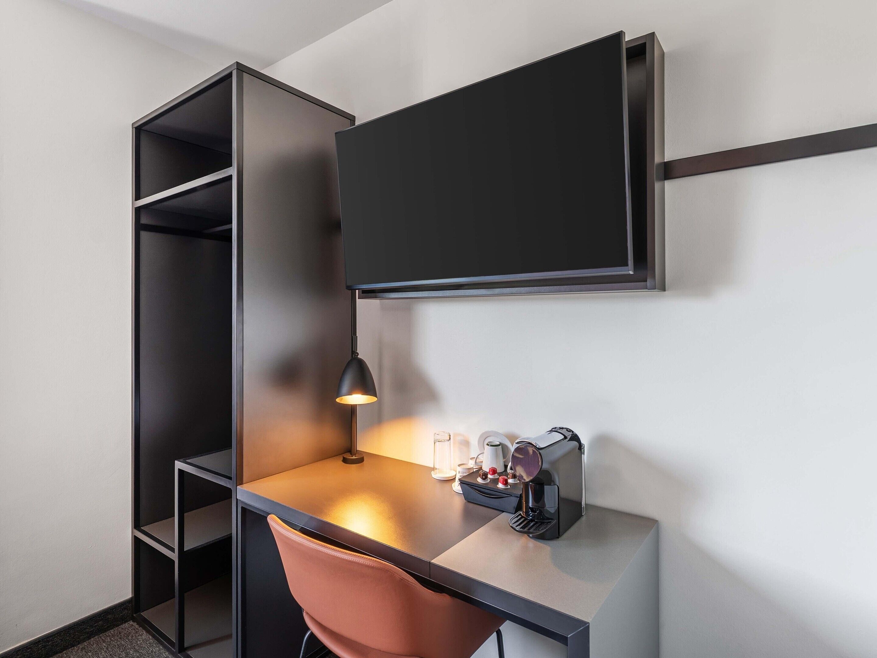 A modern, compact workspace with a desk, chair, and a mounted flat-screen TV.