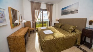 A hotel room with a bed, a desk, a chair, and a view of the sea. - Marina del Castillo 305 (Manilva)