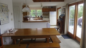 Una cocina con armarios de madera, una mesa grande de madera y una lámpara colgante.