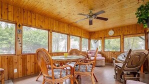Une cabane en bois avec un coin repas comprenant des chaises en osier et une table ronde.