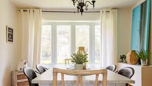 Un coin repas avec une table blanche, des chaises noires et un lustre.