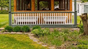 Une cabane en bois avec une véranda et une fenêtre ronde.