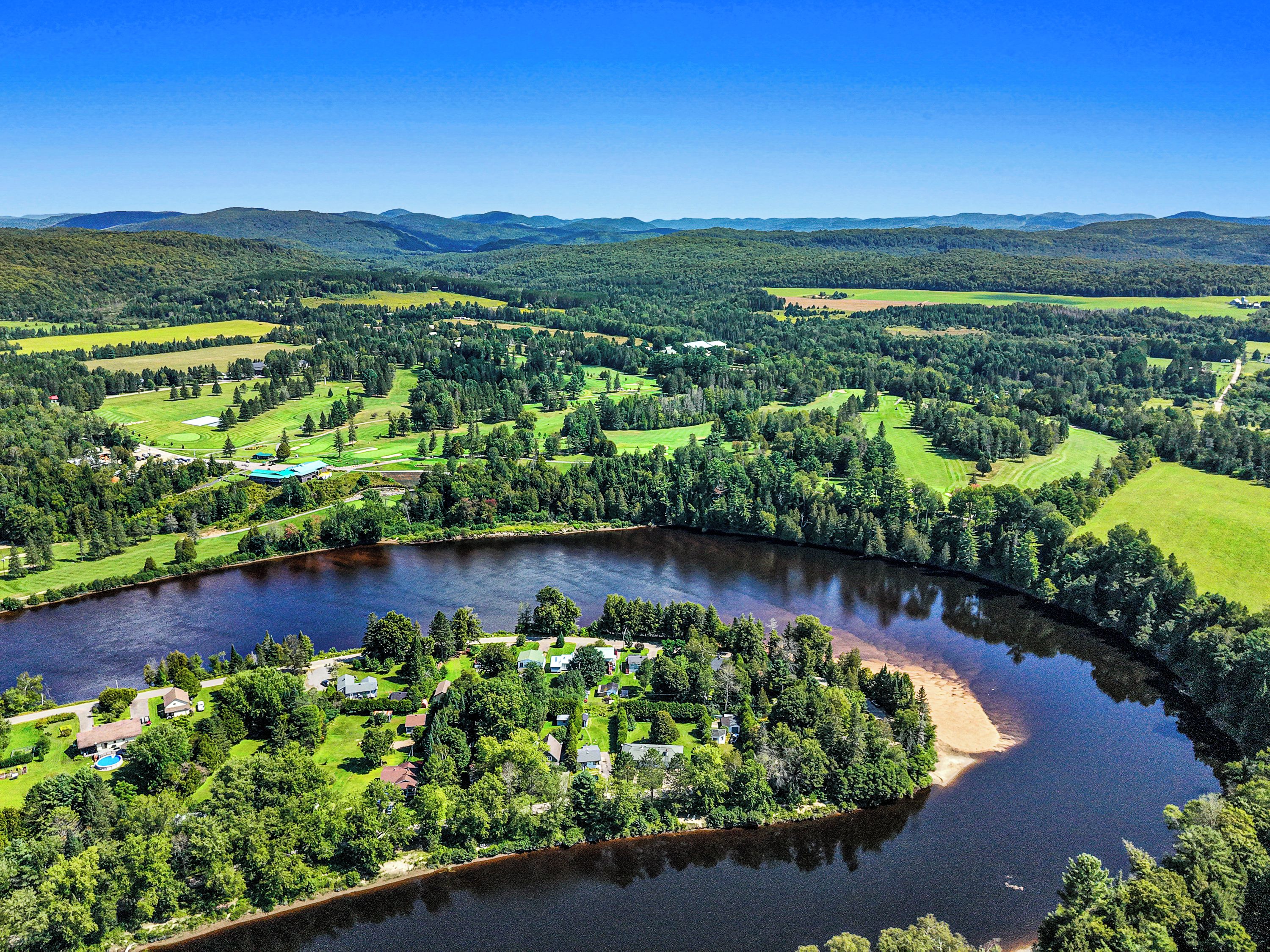 A river curving through a landscape with houses and green fields.