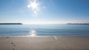 A beach with a clear sky, calm sea, and distant lighthouses. - Marina Real apto 534 (Manilva)