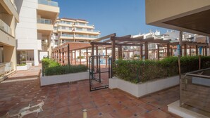 A courtyard with a wooden pergola, potted plants, and a tiled floor. - Marina del Castillo 302 (Manilva)