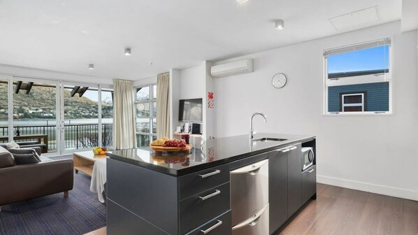 Una cucina moderna con una grande isola, elettrodomestici in acciaio inossidabile e vista su un lago.