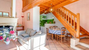 Ein gemütliches Wohnzimmer mit einem weißen Sofa, einem Esstisch mit Stühlen und einer Holztreppe.