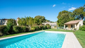 Ein rechteckiger Swimmingpool mit klarem, blauem Wasser, umgeben von einer gefliesten Terrasse und einer Rasenfläche.