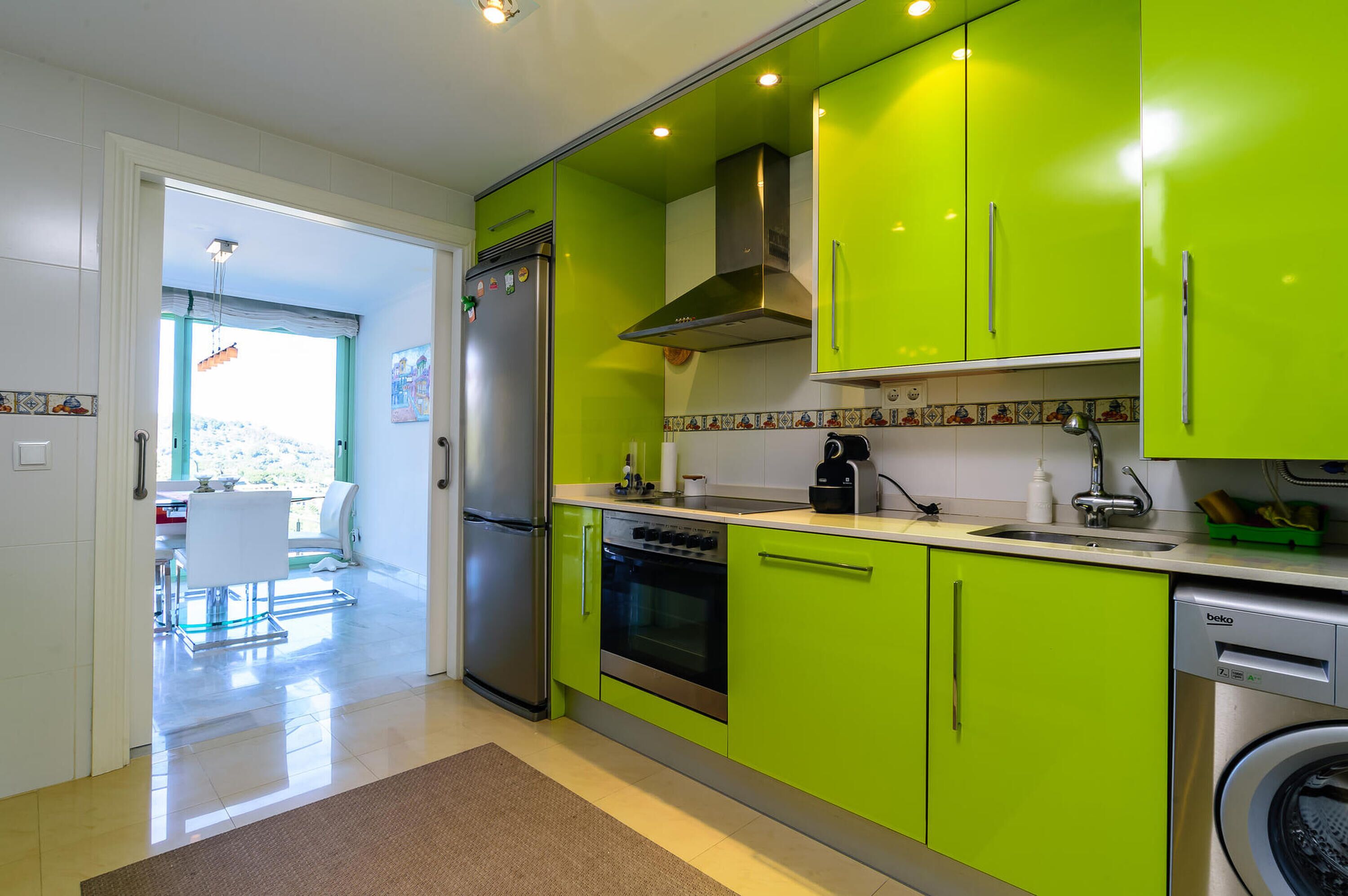 A kitchen with green cabinets, a stainless steel refrigerator, an oven, and a dishwasher.