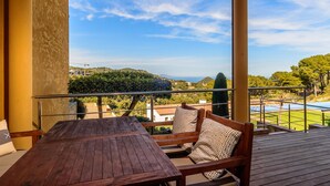 A wooden deck with a table and chairs, overlooking a pool and greenery. - Nice townhouse with comunity pool and sea views. (Begur)