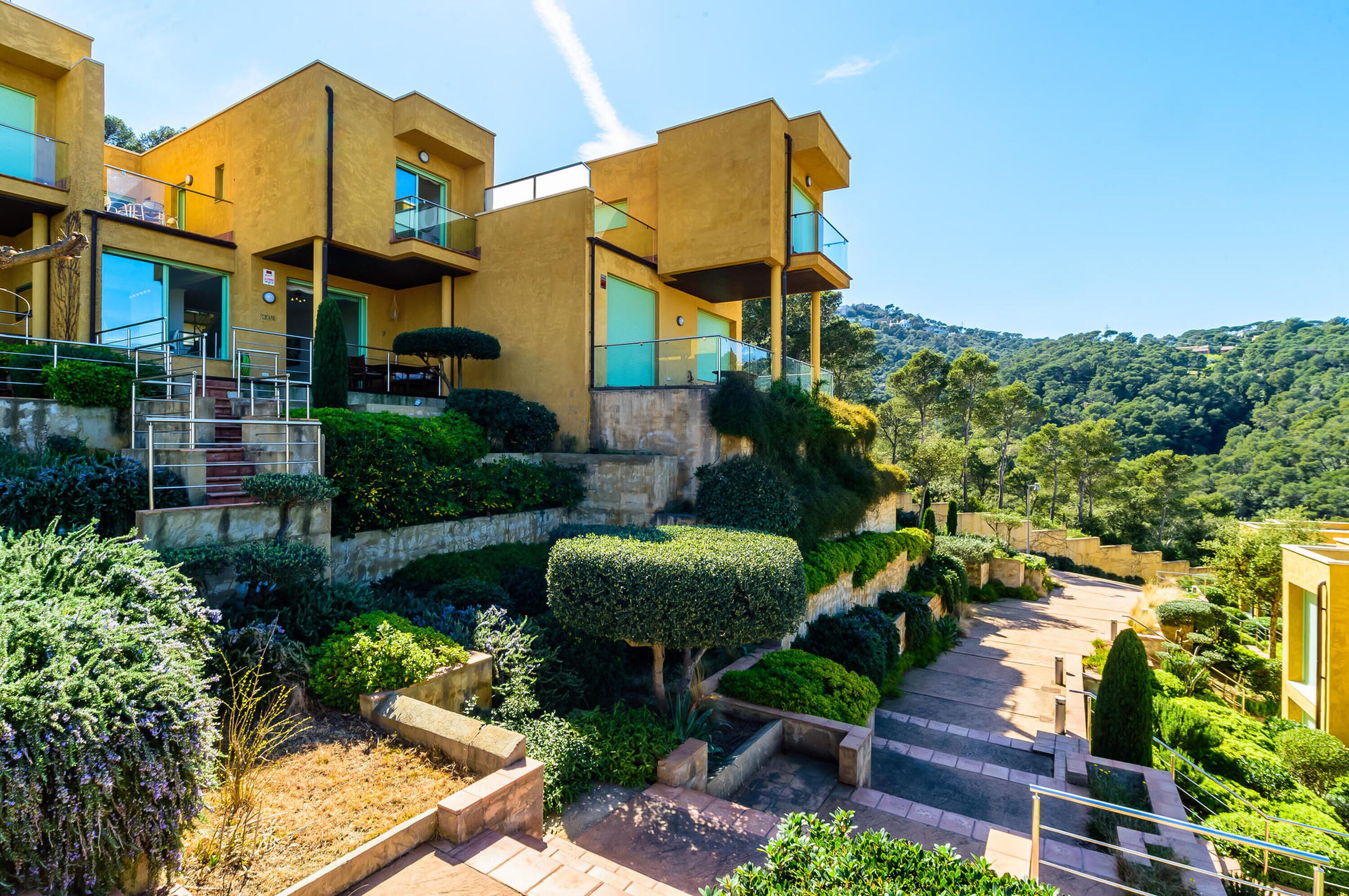 A modern building with multiple balconies and a landscaped garden.