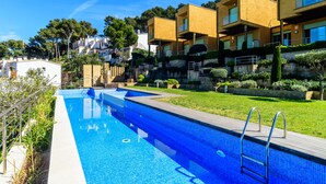 A modern residential building with a swimming pool, surrounded by greenery and a clear blue sky. - Nice townhouse with comunity pool and sea views. (Begur)