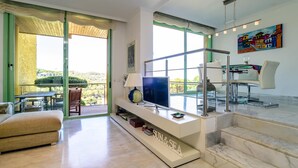 A modern living room with a TV, sofa, and dining area. - Nice townhouse with comunity pool and sea views. (Begur)