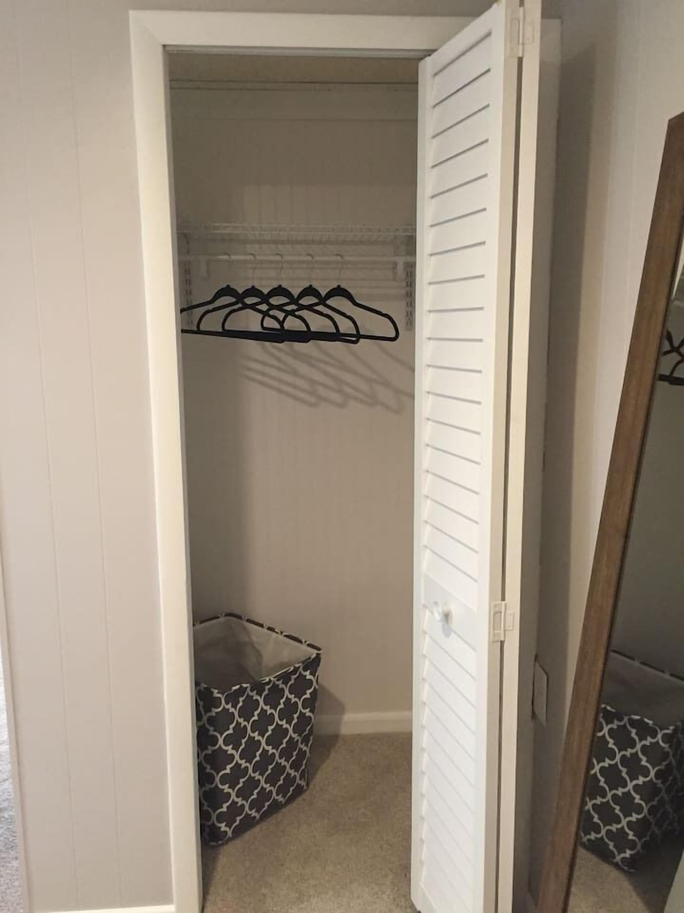 A walk-in closet with a hanging rod and a storage bin.