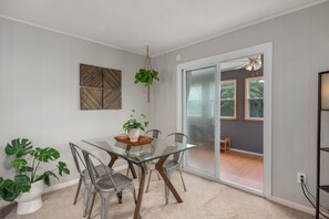 Comedor con mesa de vidrio, sillas de metal y plantas en macetas.