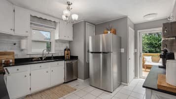 A modern kitchen with white cabinets, stainless steel appliances, and a large window.