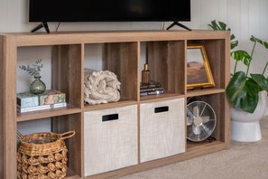 Un mueble de madera con estantes, un televisor y un ventilador.