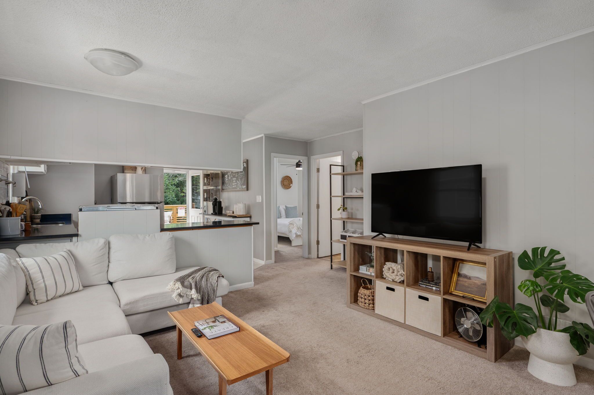 Een moderne woonkamer met een bank, salontafel en een televisie op een houten dressoir.