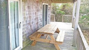 A wooden deck with a picnic table and sliding glass doors.