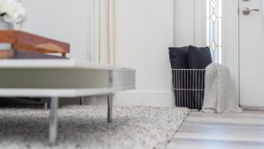 A modern room with a minimalist design, featuring a white door with a glass panel, a metal gate, and a small rug on the floor.