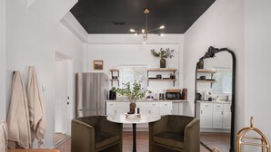 A modern kitchen with white cabinets, a central island, and a dining area with two chairs and a table.
