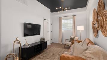 A living room with a TV, sofa, and a lamp.